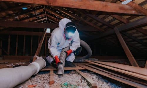 Attic Pros professional with orange gloves cleaning attic