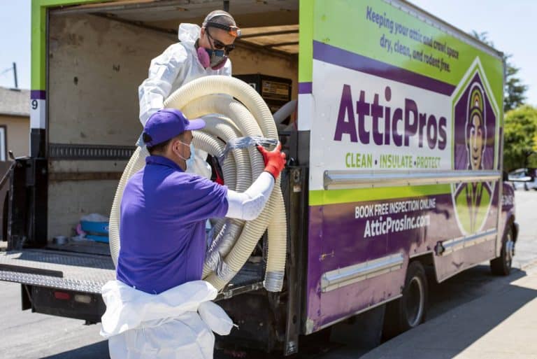 Attic Pros professionals taking tubing off of work truck