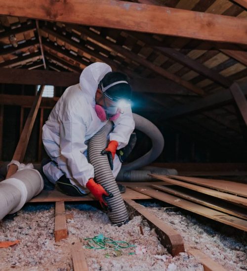 Attic Pros professional cleaning attic with uniform, mask, and orange gloves