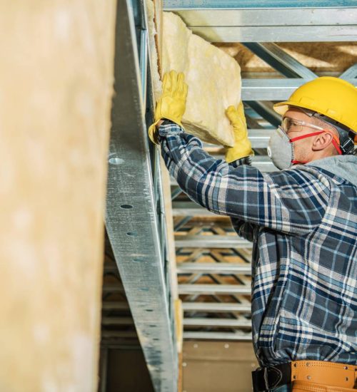 wall-insulation-installation-min Attic pros professional with plaid shirt and yellow work hat installing insulation