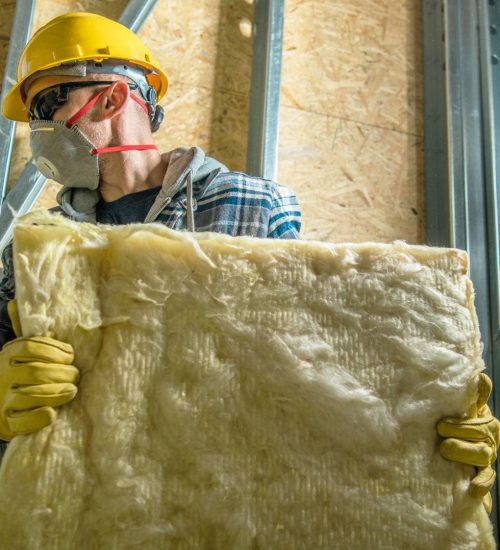 Attic Pros professional with yellow gloves and yellow hat carrying insulation